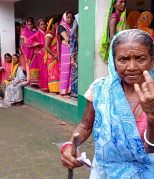 An elderly voter shows her ink-marked finger after casting a vote